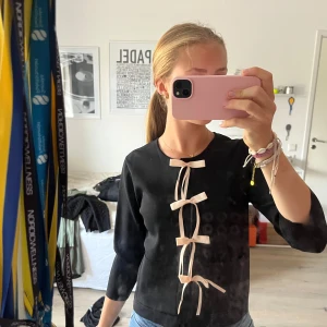 Svart kofta med rosetter från Zara - Supersöt svart kofta från Zara med ljusa rosetter framtill. Koftan har trekvartsärm, Perfekt för dig som gillar detaljer och vill ha något som sticker ut lite extra. Snygg att matcha med jeans eller kjol. Säljer pga att den inte kommer till användning, är i super bra skick 💖