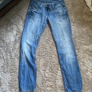 Blå straight jeans från Replay - Snygga blå jeans från Replay med klassisk femficksdesign och raka ben. Jeansen har en ljus tvätt med slitningar och kontrastsömmar. Passar dig som gillar en tidlös look och vill ha ett par jeans som funkar till det mesta. Dragkedja och knapp i midjan.