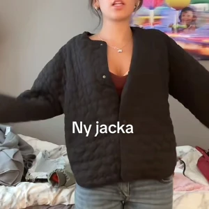 Svart quiltad jacka med hjärtan från Zara - Quiltad svart jacka från Zara med hjärtformade sömmar och rund hals. Jackan har tryckknappar framtill och en loose passform som ger en chill vibe. Perfekt för dig som gillar unika detaljer och vill sticka ut lite extra.