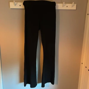Svarta bootcut byxor i stretch - Svarta bootcut byxor med hög midja och skön stretch. Sitter snyggt över höfterna och har utsvängda ben för en trendig look. Perfekta att matcha med crop tops eller hoodies. Passar dig som gillar bekväma och stilrena plagg.