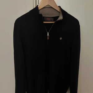Morris zip up - Snygg marinblå kofta från Morris i 100% merinoull. Tröjan har hel dragkedja, ribbad krage i kontrastfärg och en liten broderad logga på bröstet. Perfekt för dig som gillar stilrena och klassiska plagg med en modern touch. Inköpt på NK Stockholm för 1999kr för ungefär 2 månader sen 