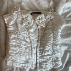 Vit korsett topp från Zara - Supersöt vit blus från Zara med smala axelband, detaljer med små blommor 