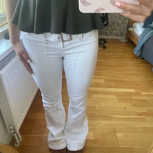 Vita bootcut jeans med bälte - Snygga vita jeans med bootcut passform och markerad söm längs benen. Mid waist med ett brett, silverfärgat bälte och metallknappar. Jeansen har en klassisk look och är gjorda i stretchigt bomullsmaterial som sitter bekvämt, därav passar de mig som ofta när S även om jeansen är i Xs. Från new yorker