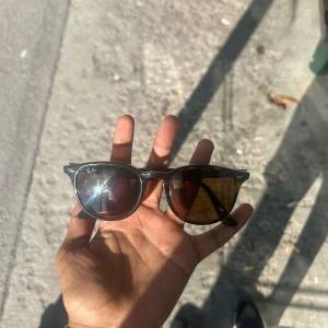 Ray-Ban bruna Wayfarer solglasögon - Snygga Ray-Ban Wayfarer solglasögon med brunmelerad båge och bruna glas. Klassisk form som alltid är trendig och passar till allt. Ikonisk Ray-Ban-logga på båda sidorna. Perfekta för soliga dagar och ger en cool vibe.