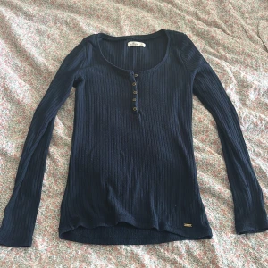 Mörkblå ribbad långärmad tröja Hollister - Snygg mörkblå långärmad tröja från Hollister med ribbad struktur och rund halsringning. 