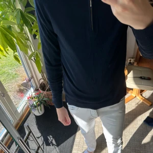 Mörkblå half zip stickad tröja Tiger of Sweden - Snygg mörkblå stickad tröja med half zip-dragkedja vid halsen från Tiger. Perfekt för dig som gillar stilrena och enkla plagg med lite edge.