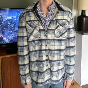 Blå och vit rutig overshirt - Sjukt snygg overshirt med mjuk fodring inuti. Perfekt för en kall sommarkväll. Det är en herr storlek S