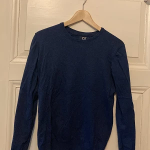 Mörkblå tröja från Cutter & Buck - En stilren mörkblå långärmad tröja från Cutter & Buck i storlek M. Tröjan har rund halsringning och är tillverkad i ett mjukt material som passar perfekt till vardags. Enkel och klassisk design utan mönster eller detaljer.