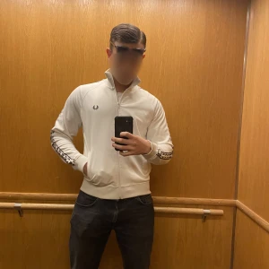 Fred Perry kofta - Fred Perry kofta i vit, svår att få tag i då det är den gammla kollektionen. Som ny, inga defekter eller fläckar. Storlek m men passar L. Säljer för att den är för liten ( 187 cm 86 kg)