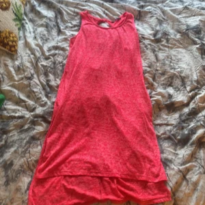Rosa klänning med cut-out detaljer - Säljer en rosa ärmlös klänning med rund hals och två snygga cut-out detaljer i ryggen. Klänningen har en lös passform och är tillverkad i ett mjukt, stretchigt material. Perfekt för varma dagar eller sommarens äventyr!