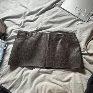 Mörkbrun minikjol i skinnimitation - Säljer en mörkbrun kortkjol i skinn imitation, använd endast 1 gång. 