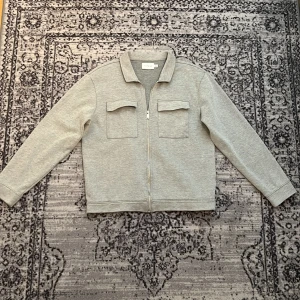 Ljusgrå zip-jacka från Topman - Säljer en stilren ljusgrå jacka från Topman, jag använder den som en overshirt på tex en hooide. Den har extrem bra passform på storlek M. 