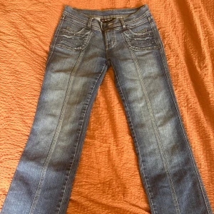 Lågmidjade jeans  - Snygga blå jeansbyxor med raka ben och dekorativa diamanter på både fram- och bakfickor. Klassisk femficksmodell med normal passform och markerade sömmar längs benen. Perfekta för en cool och avslappnad stil.💕