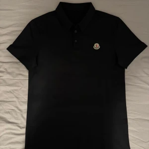Moncler piké  - Snygg svart oanvänd Moncler pikétröja slim fit med liten broderad logotyp på bröstet. Stilren klass piké helt oanvänd ett riktig bra kap, pris kan diskuteras vid snabb affär.