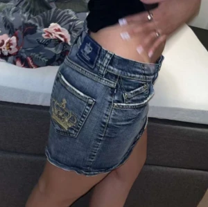 Victoria Beckham Jeanskjol 32  - Trendig jeanskjol med snyggt guldbroderi på fickorna. Perfekt för en avslappnad stil med en touch av glamour. Kjolen har en klassisk femficksdesign och en bekväm passform.