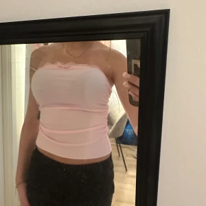 Ljusrosa tubtopp - Säljer en ljusrosa tubtopp med lätt rynkdetalj upptill. Toppen är ärmlös och har en tight passform som sitter snyggt mot kroppen. Perfekt att styla till både jeans och kjol.