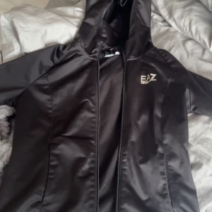 Svart tröja  med tröja från Emporio Armani EA7 - Snygg svart tröja  med huva från Emporio Armani EA7. Köpt från jd sport. passar xxs och xs 