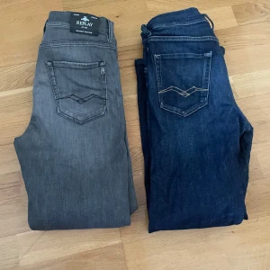 Replay jeans i grått och mörkblått - Två par Replay jeans, ett i grått och ett i mörkblått. Klassisk femficksmodell med raka ben och diskreta sömmar på bakfickorna. Perfekta för dig som gillar stilrena och tidlösa jeans. Båda jeansen är i storlek 158 för barn 