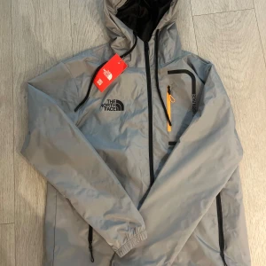 The North Face Windbreaker - Hej! Jag säljer en North Face Jacka som är helt ny! Denna jackan skyddar dig mot både regn och vind, så den är helt vättentätt., som är hjälpsamt ifall det är dåligt väder! STORLEK : S, NYSKICK. Om du har beställt varan innan 20:00, så skickas den under samma dag, om du beställer den efter 20:00, så skickas den nästa dag! Mvh