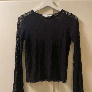Svart spetsblus från H&M - Säljer en svart långärmad blus från H&M i genombruten spets. Blusen har rund halsringning och är helt täckt av ett vackert spetsmönster. Perfekt för dig som vill ha en stilren och trendig topp med det lilla extra.