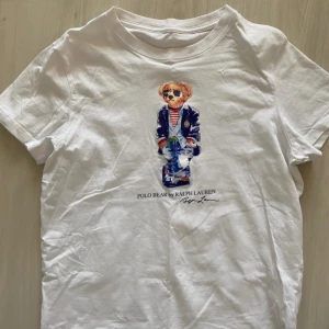 Vit t-shirt med Polo Bear från Ralph Lauren - Vit t-shirt från Ralph Lauren med ikoniska Polo Bear-trycket framtill. 