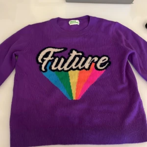 Lila tröja 100% cachemire från From Future - Säljer en lila cachemire tröja från From Future med texten 'Future' framtill och ett färgglatt regnbågsmönster i blått, grönt, gult, orange och rosa. Tröjan har rund hals och långa ärmar. Storleken är xs och nästan aldrig använt. Märket är From Future och tröjan kostar i vanliga fall ca ”2000”kr men säljer för ”750”kr med frakt.