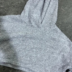 Grå croppad hoodie från SHEIN - Mysig grå croppad hoodie från SHEIN i frottéliknande material. Tröjan har långa ärmar och en stor huva, perfekt för en avslappnad och trendig look.