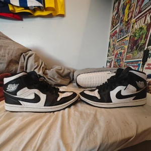 Svarta och vita Nike Air Jordans high-top sneakers - Säljer ett par klassiska Nike Air Jordans high-top sneakers i svart och vitt. Skorna har snörning, rund tå och den ikoniska Nike-loggan på sidan. Perfekta för dig som gillar streetwear och vill sticka ut med en tidlös modell. Skorna är i storlek 41 och är en speciell variant då den är ganska annorlunda små skavanker finns med mycket fint skick 