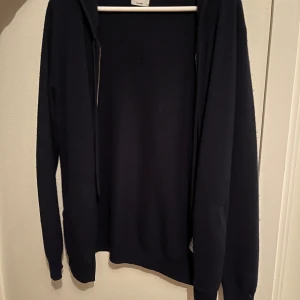 Mörkblå cashmere hoodie från John Henric - Säljer en mörkblå hoodie från John Henric i 100% cashmere. Tröjan har dragkedja, huva och långa ärmar. Perfekt för dig som vill ha något mjukt och stilrent i garderoben.