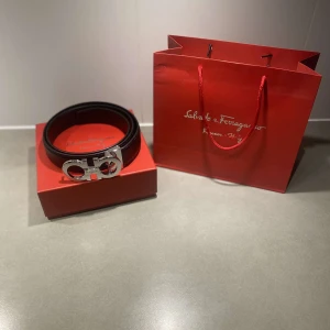 Svart skärp från Salvatore Ferragamo med silverfärgat spänne - Säljer ett svart skärp från Salvatore Ferragamo med ett ikoniskt, stort silverfärgat spänne. Skärpet är stilrent och tillverkat i skinn. Kommer med originalpåse, ask och kvitto.
