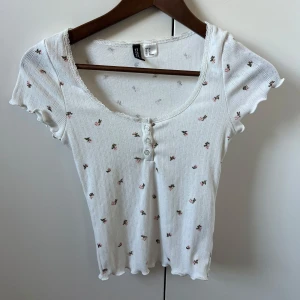 Gullig topp - Söt topp med knappar och blommor. Knappt använd. Kolla gärna in mina andra annonser och få paketpris vid köp av flera varor!