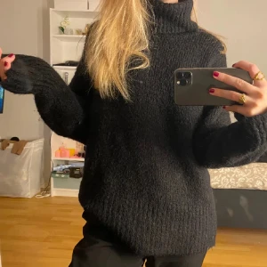 Svart stickad polotröja - Mysig svart stickad polotröja med lång ärm och hög krage. Tröjan har en lite lösare passform och är perfekt för kyliga dagar. Enkel att matcha med olika outfits och passar både till jeans och kjol.