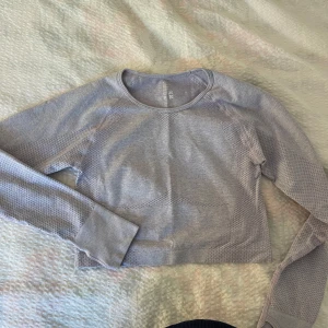  Relode topp - Säljer en ljuslila croppad träningströja från Relode. Tröjan har tumhål vid ärmsluten. Säljer du den inte kommit till användning 😍