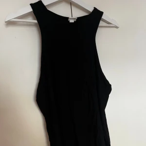 Svart ribbat linne - Säljer ett svart linne i storlek XL. Linnet har breda band  med hög halsringning och har en tight passform. Perfekt för dig som gillar en enkel och stilren look.