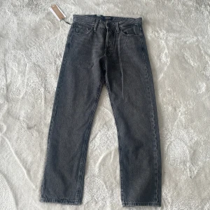Grå jeans från Jack & Jones - Snygga grå jeans från Jack & Jones med klassisk femficksdesign och raka ben. Jeansen har normal passform och är tillverkade i denim. Perfekta för dig som gillar en stilren look. 
