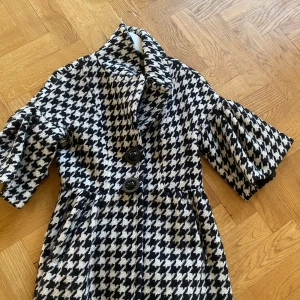 Svartvit rutig kappa från Jesiré - Säljer en snygg svartvit kappa från Jesiré. Jackan har stora knappar framtill, bred krage och trekvartsärmar. Den är endast använd ett fåtal gånger och har inga skavanker eller defekter❤️