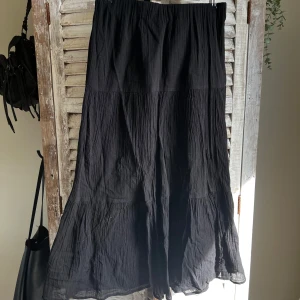 Svart långkjol från Gina Tricot - Säljer en svart långkjol från Gina Tricot. Kjolen har en luftig och lätt struktur med resår i midjan och ett diskret volangparti nedtill. Perfekt för dig som gillar en enkel men stilren look.