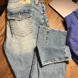 True religion ljusblå jeans - Säljer ett par true religion jeans i ljusblå tvätt och modellen ”billie”. Storlek 28 i deras storlekar (motsvarar storlek 38/M) De är i bra väldigt bra skick förutom en slitning längst ner vid ett av benen (se bild).