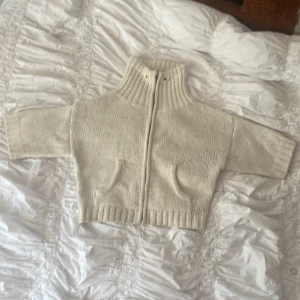 Beige stickad kofta  - Säljer en beige stickad kofta med grov ribbad polokrage och dragkedja framtill. Koftan har två fickor och är i ett mjukt, tjockt material som passar perfekt när det är kyligt. Jag köpte den begagnad för inte så länge sedan men jag har inte använt den, den har några få deffekter, som smink på insidan, säkert något man kan tvätta bort, dragkedjans huvud har inget handtag men man kan knyta ett snöre istället. 