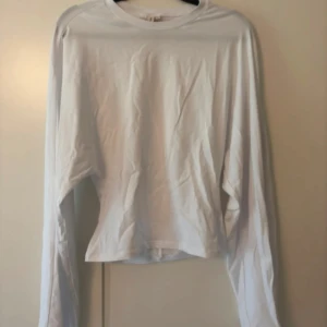Vit långärmad tröja från Nelly - Enkel och stilren vit långärmad tröja från Nelly i mjuk bomull. Tröjan har rund halsringning och en rak passform som funkar till många olika looks. Perfekt basplagg för garderoben.