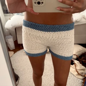 Stickade shorts i blått och vitt - Unika virkade shorts med bred midja i blått och vita partier. Perfekta för sommaren och till stranden. Materialet är virkad och är bekväma. Snygga kontraster mellan blå och vit, passar till mycket.
