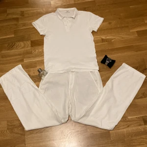 Vit pikétröja från Kappahl - Klassisk vit pikétröja från Kappahl i storlek 158/164. Tröjan har korta ärmar, krage och knappar framtill. Tillverkad i mjuk bomull som är skön mot huden. Perfekt för en clean och stilren look. Ändas tröjan medföljer vid köp.