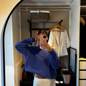 Blå croppad stickad tröja - Säljer en blå croppad stickad tröja med loose passform och långa ärmar. Tröjan har en enkel design med ribbade muddar vid ärmslut och halsringning. Perfekt för dig som gillar en avslappnad och trendig stil.