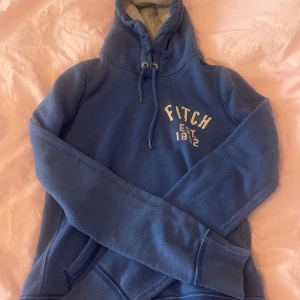 Blå hoodie från Abercrombie & Fitch - Snygg blå hoodie från Abercrombie & Fitch med broderad logga på bröstet och snörning i huvan. Storlek L men är väldigt liten i storleken så skulle säga att den sitter mer som en liten M stor S i storleken 
