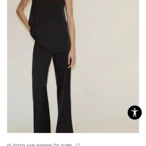 Svart axelbandslös tubtopp i satin - Snygg svart axelbandslös tubtopp i glansigt satinmaterial. Toppen har en enkel och stilren design med rak passform och elastisk kant upptill för att sitta på plats. Från Zara ny köpt aldrig använd men lappen råkade trilla av vid provning. 