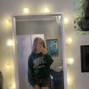 Grön sweatshirt från SHEIN - Mörkgrön sweatshirt från SHEIN med tryck framtill där det står 'WEST COAST'. Tröjan har rund hals, långa ärmar och ribbade muddar vid ärmslut och nederkant. Perfekt för en chill och avslappnad stil. Man får tröjan ny tvättad och strykt. 