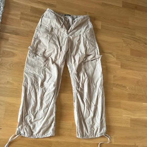 Beige cargopants från Gina Tricot - Säljer ett par beige cargopants från Gina Tricot i storlek S. Säljs då jag inte använder de så mycket längre. Byxorna har flera fickor på sidorna. Det finns dragskedja  i midjan och ett snöre som man kan knyta samt vid benen. Perfekta för en chill och avslappnad stil.