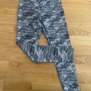 Träningsbyxor från Röhnisch - Snygga leggings från Röhnisch i storlek XS med svart, grått och vitt grafiskt mönster. De är stretchiga och sitter tight.