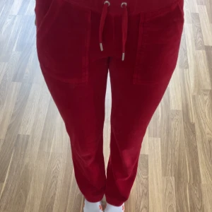 Röda mjukisbyxor Juicy Couture XXS - Riktigt snygga röda mjukisbyxor från Juicy Couture i storlek XXS. Byxorna har dragsko i midjan, stora fickor fram och är gjorda i mjuk och skön velour. Perfekta för en chill och trendig look.