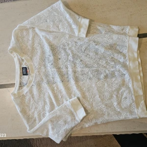 Vit spetsblus från ONLY - Superfin vit blus från ONLY i spets med blommigt mönster. Kortärmad modell med ribbade muddar vid ärmslut och halsringning. Perfekt för dig som gillar romantisk och feminin stil. Säljes i storlek S.